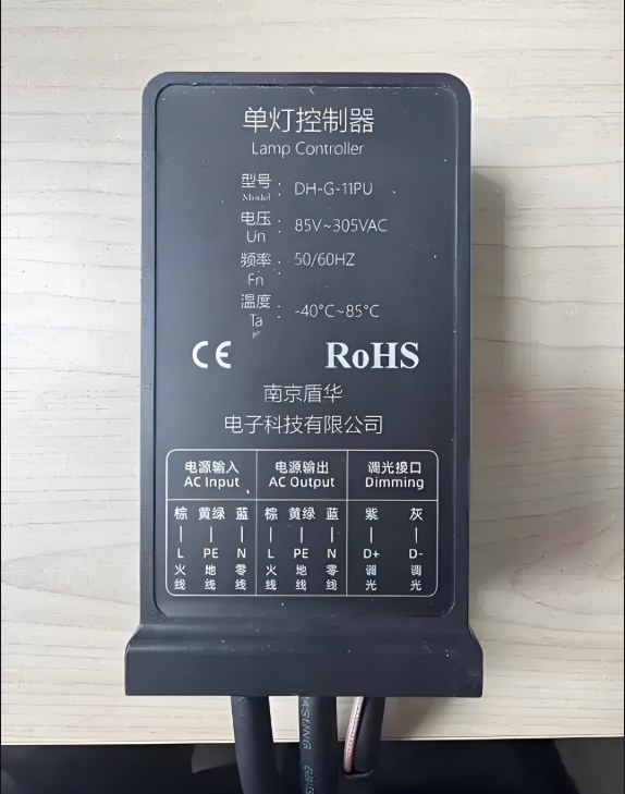Photo of the DH-G-11PU single lamp controller by Nanjing Dunhua Electronics, showing input/output wiring terminals, AC voltage range of 85–305VAC, and dimming interface with RoHS and CE certifications.